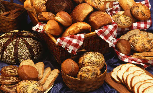 다양한 종류의 빵이 파란색 천에, 일부는 바구니에, 일부는 시트에 배열되어 있습니다.